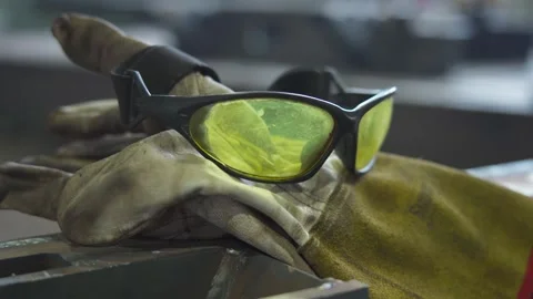 Protective glasses and work gloves on metal table in industrial workshop Stock Footage 306179631