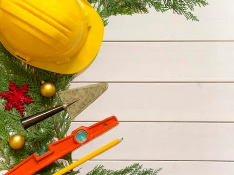 Protective helmet, mason tools  and Christmas decorations on wooden white bac Stock Photos