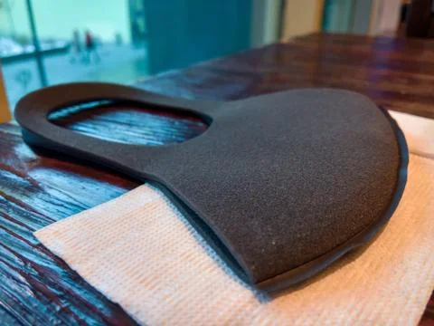 A protective mask of black foam material is placed on a white napkin on a woo Stock Photos