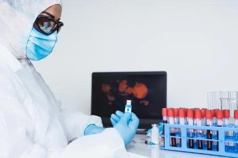 Protective mask, blood sample tubes and laptop with lab technician hands on Stock Photos