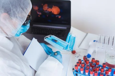 Protective mask, blood sample tubes and laptop with lab technician hands on Stock Photos
