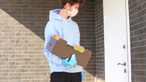 Protective masked courier and glove deliver food to woman Stock Footage 129833829