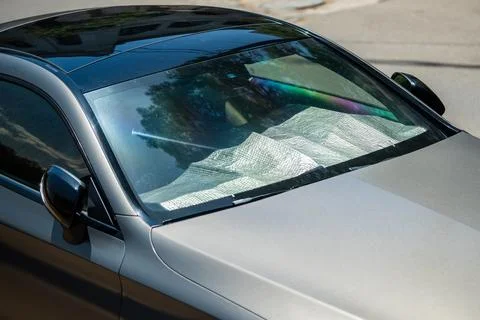 Protective reflective surface under windshield of passenger car parked on hot Foto stock
