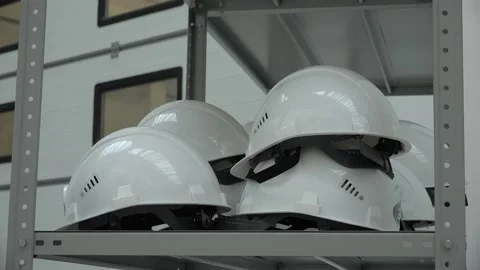 Protective white helmets hang on the rack in the factory. Stock Footage 159667273