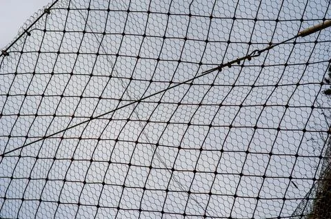 Protective wire mesh net stretched outdoors against blue sky background Stock Photos