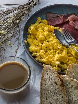 Protein breakfast with scrambled eggs, bacon, bread and coffee Stock Photos