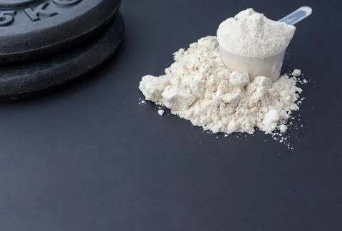 Protein Powder on dark with weights plates Stock Photos
