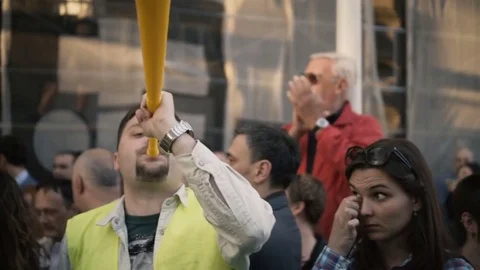 Protes on streets. Protester blows large yellow pipe wind instrument in a crowd Stock Footage 75033927