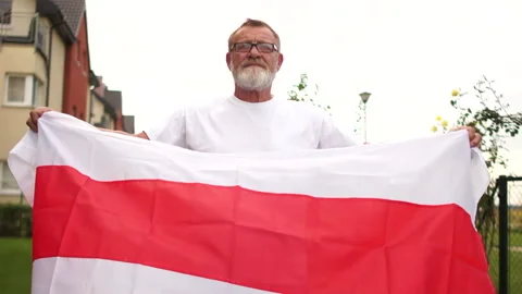 Protest in Belarus. A man holds the flag of Belarus and stretches it with his Stock Footage 139106850