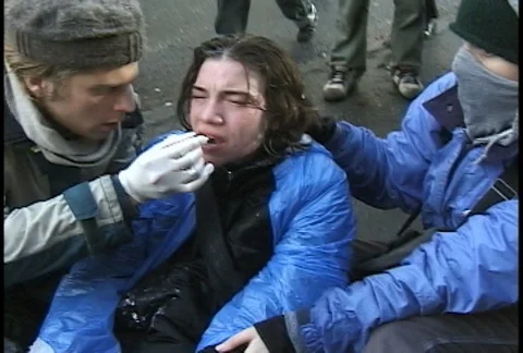 Protester Helping Tear Gassed Man at WTO Protests Stock Footage 106852901