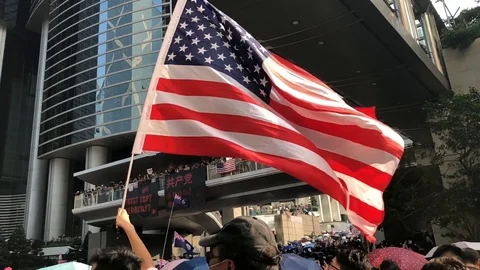 Protester holding US flag marching to the US consulate in slow motion Stock Footage 115707162