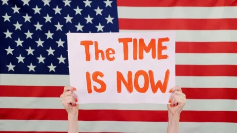Protester holds a banner with a slogan - The Time is now - against background of Stock Footage 132003541