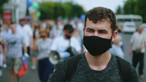 Protester man in covid facemask walking in restrictions opposition people crowd. Stock Footage 160973638