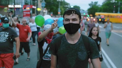 Protester man in covid facemask walking in restrictions opposition people crowd. Stock Footage 160979297