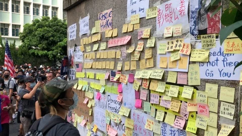 Protester sticking sticky notes on wall of US consulate. Protester at the back Stock Footage 115707051