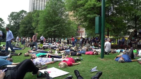 Protesters lying down on green field during rally against Trump Stock Footage 76835715