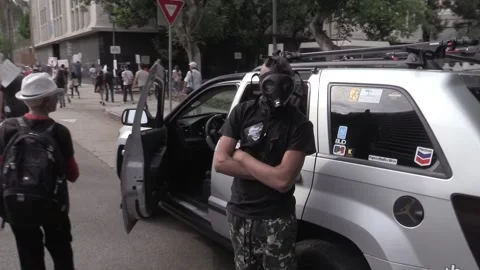 Protesters  Pass By a Boy Wearing a Gas Mask at an Anti-Trump Demonstration 스톡 동영상 225352111