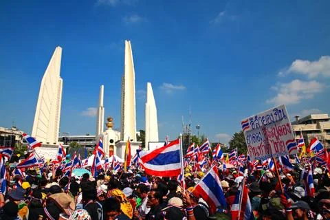 Protesters raise thai flags and banner at democracy monument Stock Photos