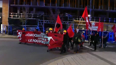 Protesters in red turning corner Stock Footage 99875383