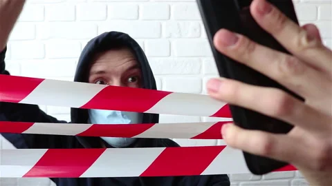 Protesting man in hoodie and face mask behind the warning tape using smartphone Stock Footage 153005338