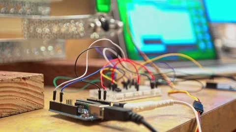 Prototype circuit with wires and microcontroller on desk beside laptop for Stock Footage 332233005