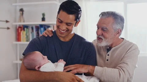 Proud Hispanic father holding his four month old son at home, with grandfather Stock Footage