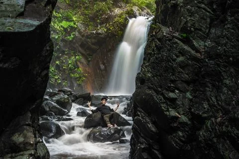 Proud man lying in the middle of river. Beautiful landscape with waterfall,.. Stock Photos