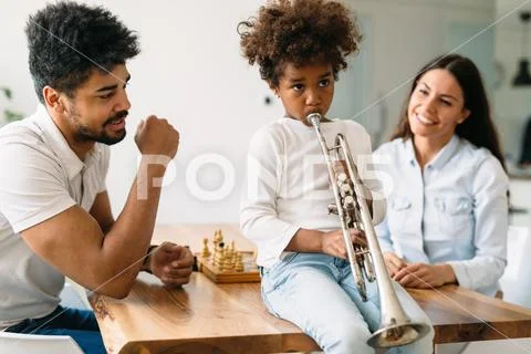 Proud parents watching their child plays trumpet Stock Photos