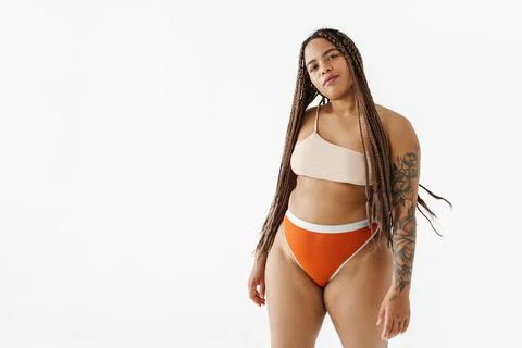 Proud young african bodypositive woman in swimwear standing over white backgr Stock Photos