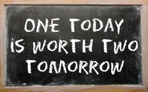 Proverb "one today is worth two tomorrow" written on a blackboard Stock Photos