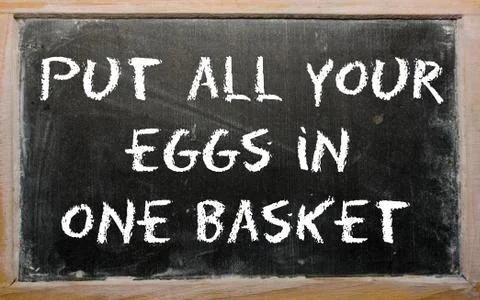 Proverb "put all your eggs in one basket" written on a blackboard Stock Illustration