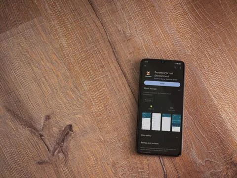 Proxmox Virtual Environment app play store page on smartphone on wooden bac.. Stock Photos