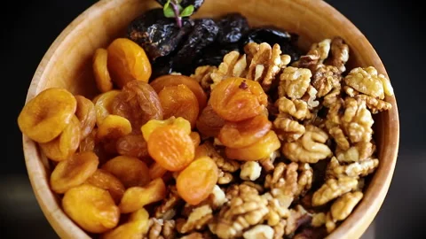 Prunes, dried apricots and nuts in a wooden bowl on a dark background Stock Footage 304091838