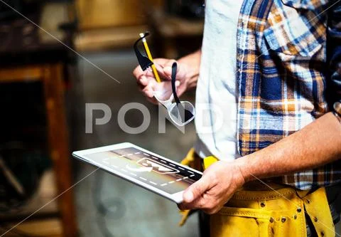 PSD template of carpenter standing in workshop and using digital tablet PSD Template