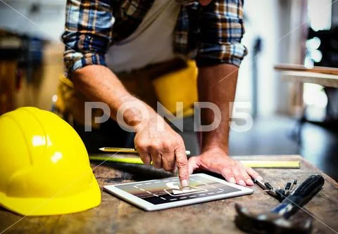 PSD template of carpenter using digital tablet at wooden table in workshop PSD Template