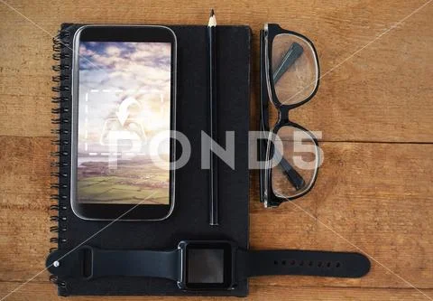PSD template of diary, smart watch, pencil, spectacle and mobile phone on wooden PSD Template