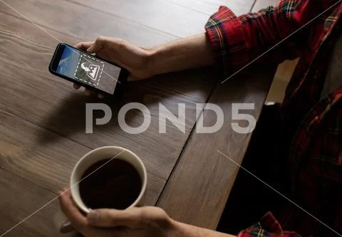 PSD template of man using mobile phone while having coffee at table in home PSD Template