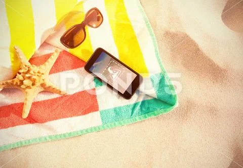 PSD template of smart phone kept on a towel at beach PSD Template