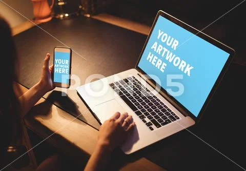 PSD template of woman using mobile phone while working on laptop at dining table PSD Template