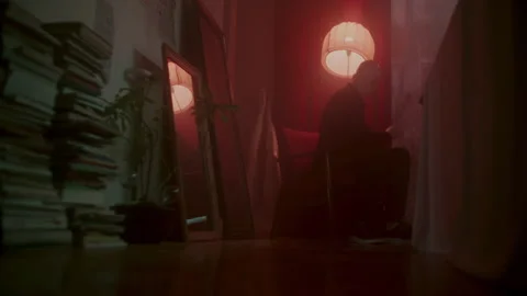 Psycho Writing something under red light and books on the left Vídeo Stock 259851502