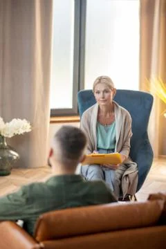 Psychoanalyst making some notes while listening to patient Stock-Fotos