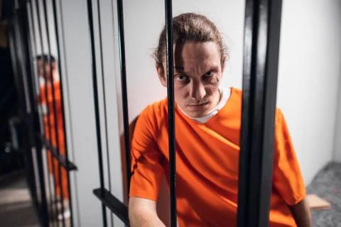 Psychological portrait of an evil and wild prisoner through the bars of a prison Stock Photos
