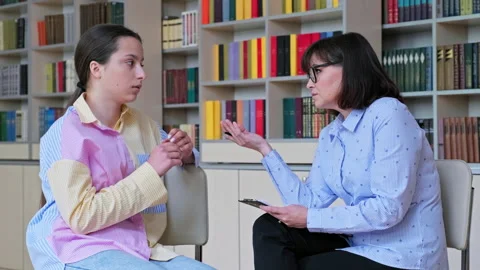 Psychologist, high school behavior counseling teenage student in library Stock Footage 196128988