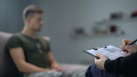 Psychologist making notes during therapy session with sad male soldier, PTSD Video stock 108454801