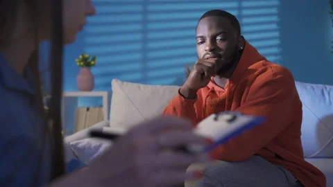 Psychologist taking notes during therapy session with upset black man.  Stock Footage 228807273