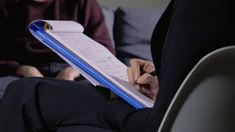 Psychologist taking notes on her block during patient session - close up Stock Footage 104874255