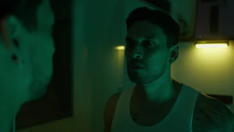 Psychotic Man in Dramatic Lighting with Intense Expression Indoors Stock Footage 319758815