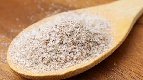 Psyllium husk (Ispaghula) falling down into a wooden spoon close up Stock Footage 303890755