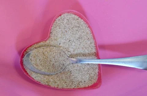 Psyllium in the shape of a heart on a pink background, top view. Super food Stock Photos