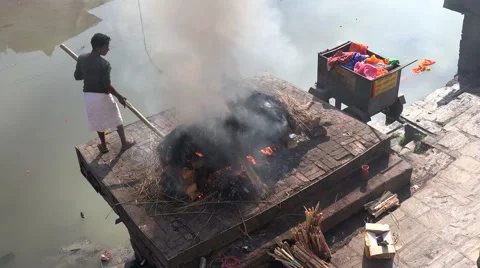 Public cremation in Kathmandu, a worker puts hay on the fire, Nepal religion Stock Footage 48784615